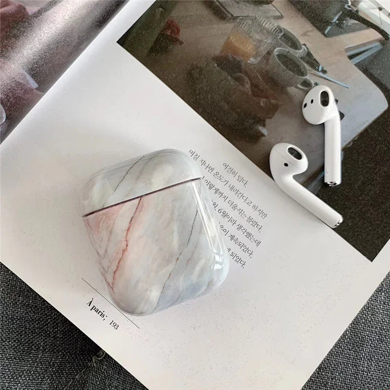 Marble-pattern AirPods case with wireless earbuds on an open magazine
