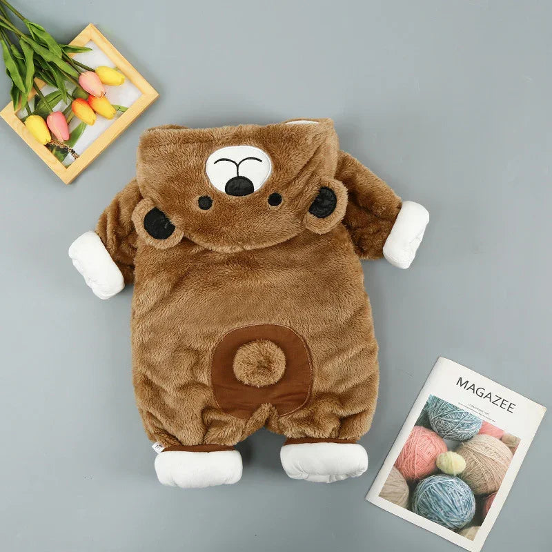 Brown bear onesie baby romper with hood, soft plush fabric, flat lay with flowers and magazine