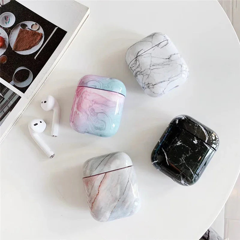 Marble pattern AirPods cases in assorted colors on a white table with wireless earbuds