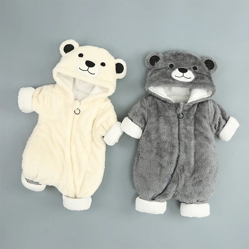 Two plush baby bear onesies, one cream and one gray, with hoods and bear faces on a gray background