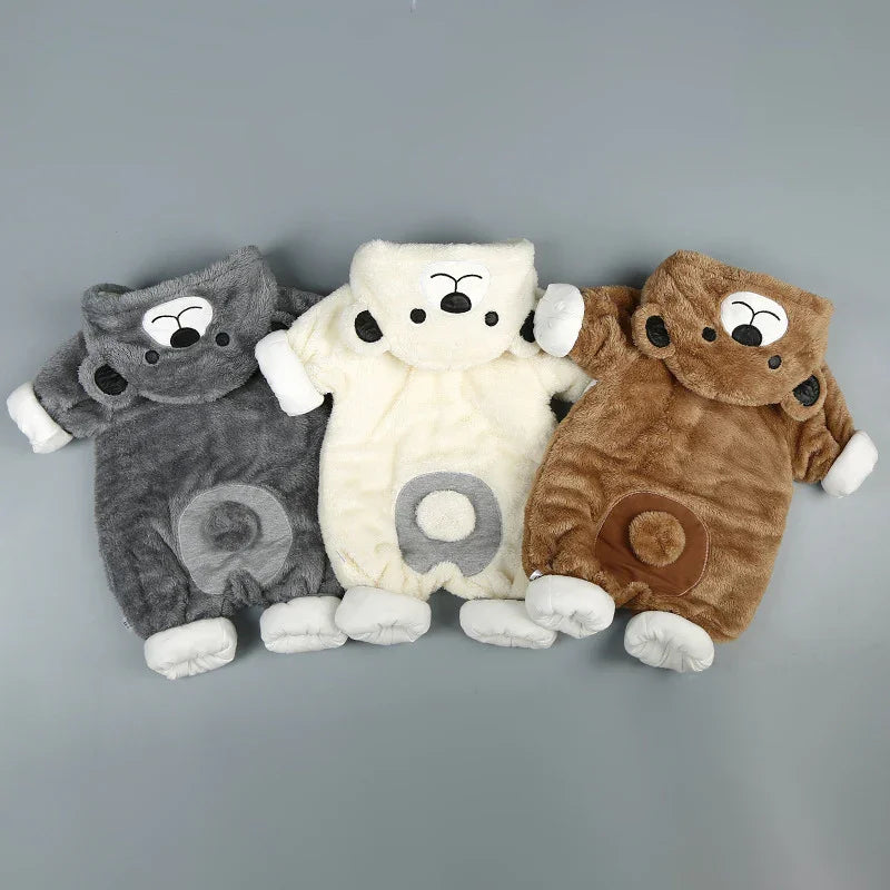Three plush animal baby onesies in gray, cream, and brown on a neutral background