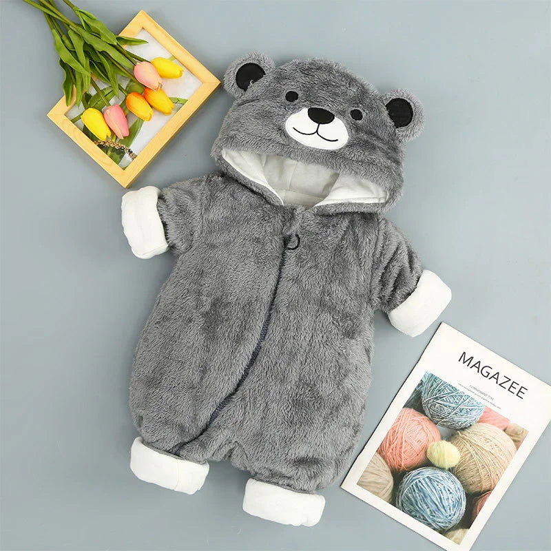 Gray bear hooded baby romper with white cuffs, tulips, and yarn magazine on gray background